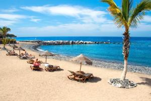 a beach with chairs and palm trees and the ocean at Casa Juanita in Playa de San Juan