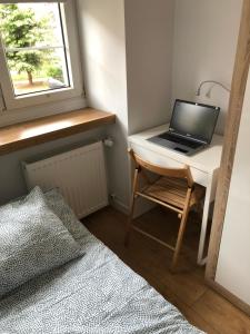 a laptop computer sitting on a desk next to a bed at Silver Apartments - Orientarium,Aquapark Fala & Park in Łódź