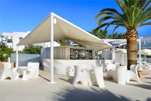 un grupo de sillas blancas, una mesa y una palmera en Blanco Hotel Formentera, en Es Pujols