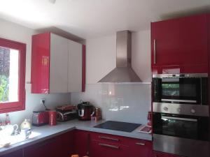 a kitchen with red cabinets and a stove top oven at VILLA DE CHARME sur la Côte d'Azur in Tourrette-Levens
