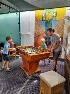 un hombre y dos niños jugando con una mesa con un tablero de ajedrez en Paracas Camp Lodge & Experiences, en Paracas