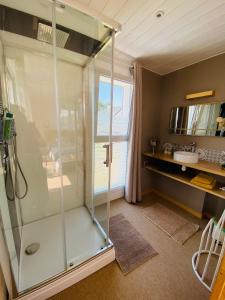 a shower with a glass door in a bathroom at Escale à 2 dans le Skiff, bord de mer et spa in Barneville-Carteret