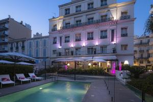 um hotel com piscina em frente a um edifício em Hôtel Le Canberra em Cannes