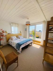 a bedroom with a bed and a large window at Escale à 2 dans le Skiff, bord de mer et spa in Barneville-Carteret