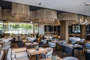 un ristorante con tavoli, sedie e lampadari a braccio di Hotel Vinifera Wine & Spa 5 Stars Superior a Balatonfüred