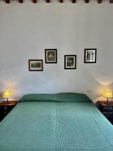 a bedroom with a green bed with three pictures on the wall at Fattoria Montignana in San Casciano in Val di Pesa