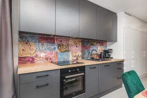 kuchnia z szarymi szafkami i kolorową ścianą wyłożoną kafelkami w obiekcie Luxurious Little Laguna Apartments SPA & Gym by Renters Prestige w mieście Międzywodzie