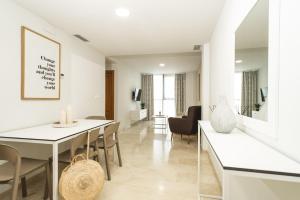 a white dining room with a table and chairs at Apartamentos Magic Atrium Plaza in Benidorm