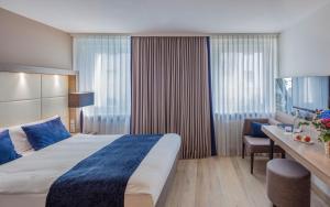 ein Hotelzimmer mit einem großen Bett und einem Schreibtisch in der Unterkunft The Alex Hotel in Freiburg im Breisgau