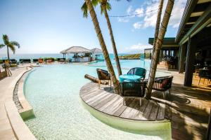 a pool with chairs and a table next to the ocean at La Toubana Hotel & Spa in Sainte-Anne