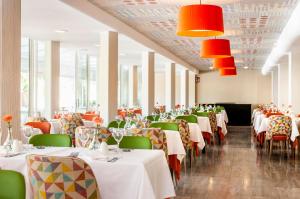 un comedor con mesas blancas y sillas verdes en Hotel Clumba en Cala Ratjada