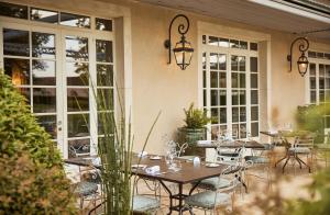 a patio with tables and chairs and windows at COMO Le Montrachet in Puligny-Montrachet