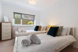 zwei Betten in einem weißen Zimmer mit Fenster in der Unterkunft Merlins Gardens in Tenby