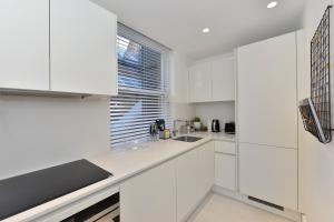 a white kitchen with white cabinets and a window at James Street Serviced Apartments by Globe Apartments in London