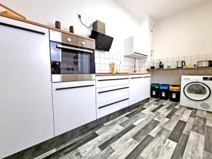 a kitchen with white cabinets and a washer and dryer at HappySide - iNDUSTRiAL DESiGN - KÜCHE - CiTY NAH - in Leipzig