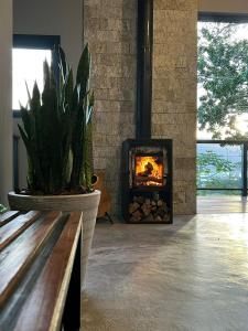 a fireplace in a room with a bench and a plant at Casa Buda - Garopaba - SC in Garopaba