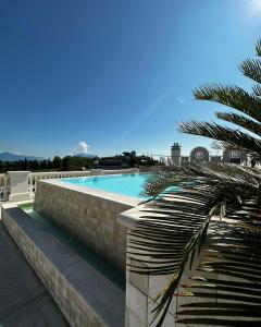 einen Pool mit einer Ziegelwand und einer Palme in der Unterkunft Palace Hotel in Desenzano del Garda