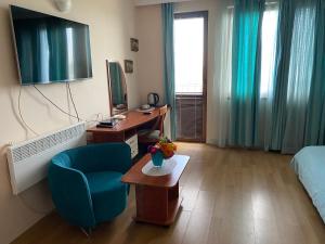 a room with a bed and a desk and a blue chair at Guest House Golden Flake 4km from Bolata beach in Bŭlgarevo