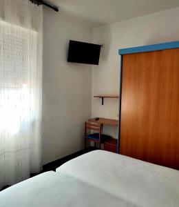 1 dormitorio con 1 cama y puerta de madera en Albergo Villa Mimosa, en Nago-Torbole