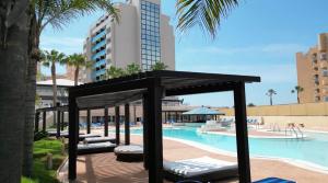 een zwembad met een zwarte structuur naast een resort bij 4Us LA MANGA VIP HOTEL in La Manga del Mar Menor