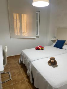 ein Teddybär, der auf zwei Betten sitzt in der Unterkunft Apartamento premium Canela Park in Isla Canela