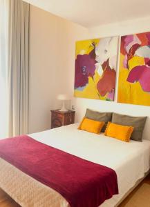 a bedroom with a large bed with colorful paintings on the wall at Quinta de Fiães in Vilar de Maçada +91 photos