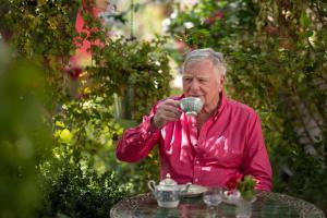 an older man sitting at a table drinking from a cup at Aal Cachucho in San Agustín de Guadalix