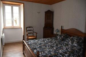 um quarto com uma cama, uma cadeira e uma janela em Le hameau de Donnedevie em Marcillac-la-Croisille