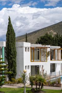 a white house with trees and a hill in the background at Chaupimundo Lodge in Quito