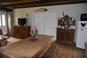 uma sala de estar com uma mesa de madeira e um frigorífico em Le hameau de Donnedevie em Marcillac-la-Croisille