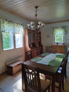 a dining room with a table and chairs and windows at Ilmastoitu huvila ja rantasauna in Keuruu
