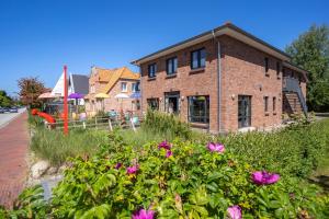 Una casa de ladrillo con flores rosas delante. en Dorfplatz Appartement Dorfplatz, en Olsdorf