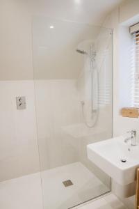 a white bathroom with a shower and a sink at Hertford Barn conversion in Hertford