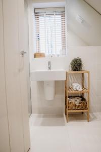 a white bathroom with a sink and a window at Hertford Barn conversion in Hertford