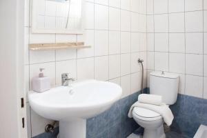 a white bathroom with a sink and a toilet at Margaret Apartments in Lefkimmi