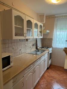 een keuken met witte kasten en een fornuis met oven bij Kalmár Apartman in Veszprém