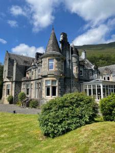 ein altes Steinhaus mit Turm in der Unterkunft Kilchurn Suites in Loch Awe