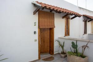 una casa bianca con una porta in legno e alcune piante di Adriatic Suite - Casa vacanze a SantʼAndrea