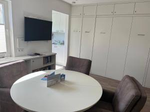 Zimmer mit einem weißen Tisch und Stühlen sowie einem TV in der Unterkunft Meike 2 - Ebenerdige Wohnung mit Terrasse und kleinem Garten in Wangerooge