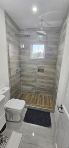 uma casa de banho com um chuveiro, um WC e uma janela. em 03Villa em Christ Church