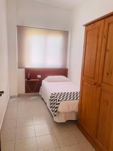 1 dormitorio pequeño con 1 cama y armario de madera en Apartamentos azayara, en La Frontera