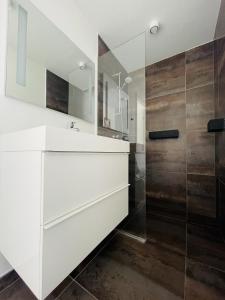 a white bathroom with a sink and a shower at aday - Elegant Apartment with Terrace in Svenstrup