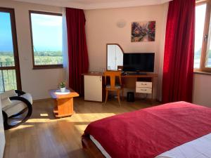 a bedroom with a bed and a desk with a television at Guest House Golden Flake 4km from Bolata beach in Bŭlgarevo