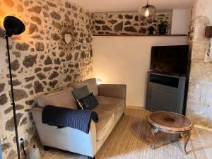 uma sala de estar com um sofá e uma televisão de ecrã plano em La Pêche em Piégut-Pluviers
