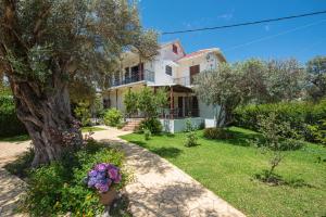 a house with a tree and flowers in the yard at Perispit in Lefkada