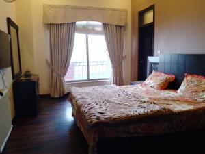 a bedroom with a bed and a large window at Noor Villa in Khaira Gali