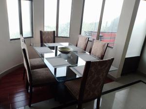 a dining room with a table and chairs with windows at Noor Villa in Khaira Gali