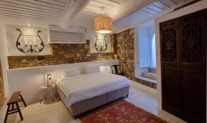 a bedroom with a white bed and a stone wall at Ipekyol Hotel in Cesme