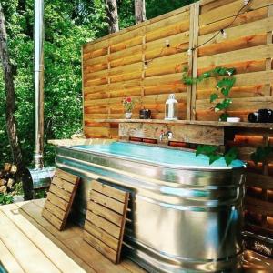 a hot tub in a backyard with a wooden wall at Cabane Bivouac avec échelle à l'ombre des chênes in Idrac-Respailles