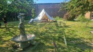 una estatua de una mujer parada en un patio con una tienda de campaña en Stargazer bell tent secret garden glamping, 